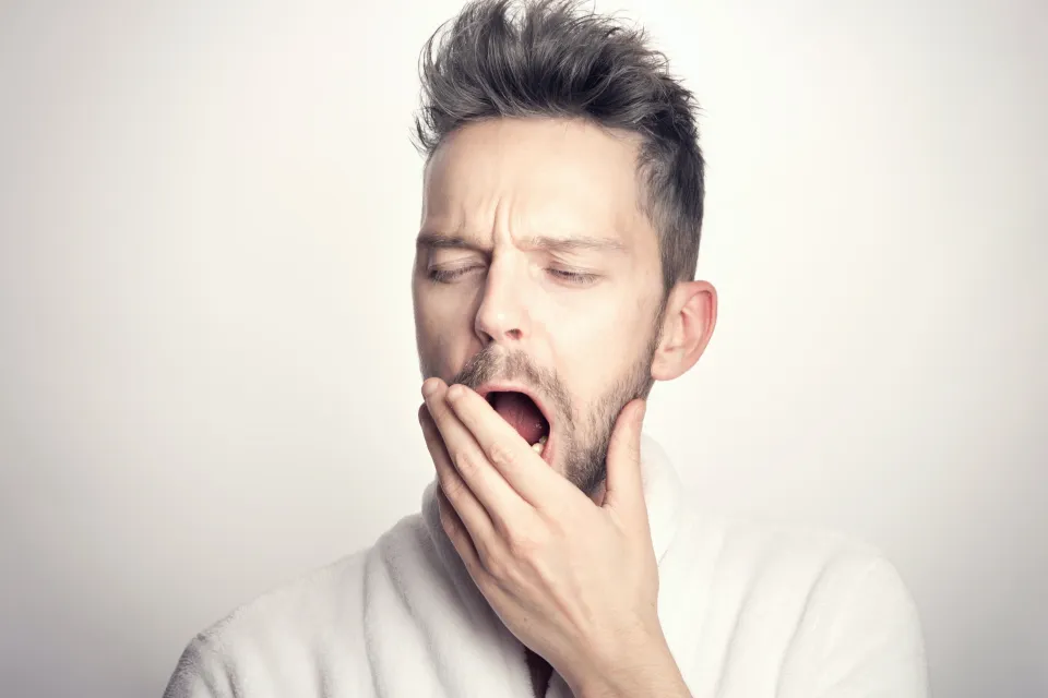 yawning man in white long sleeve shirt