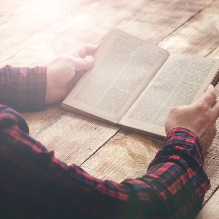 Christian businessman sitting at a desk with an open Bible and notebook, thinking carefully about business growth and stewardship