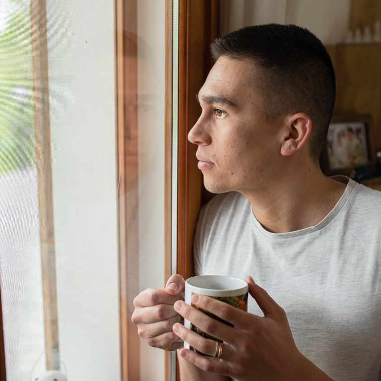 father looking out window reflecting on time, responsibility, and the life unfolding in the present