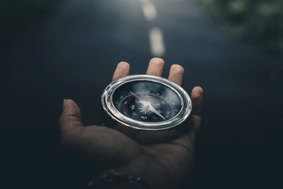 a hand holds a compass to determine which direction to go