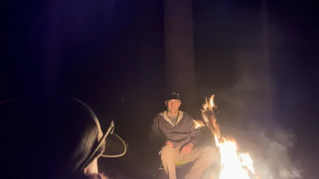 Men gathered around a campfire, engaged in deep conversation under the stars.