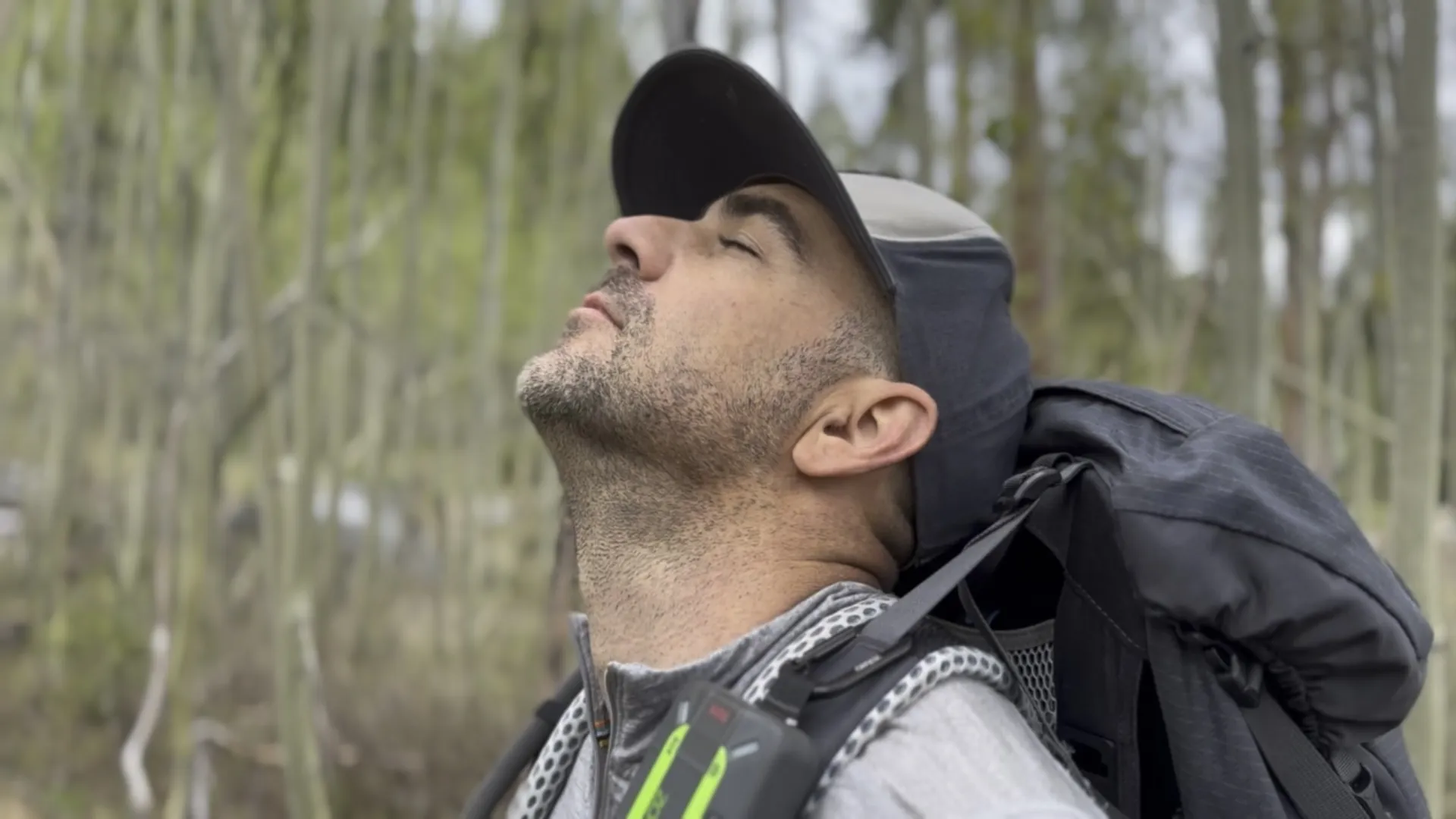 A man standing quietly in a forest praying in stillness.