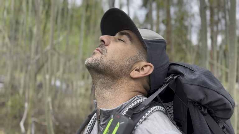A man standing quietly in a forest praying in stillness.