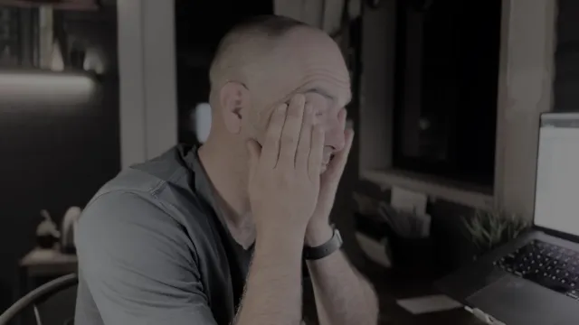 A small business owner feeling overwhelmed by financial stress, surrounded by bills and paperwork.