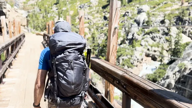 A man walking cross a rugged mountain bridge