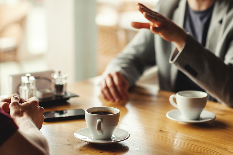 Two men sitting at a coffee shop talking deeply