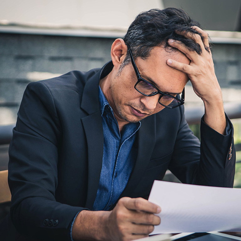 A man stressed by the weight of business finances starting at reports