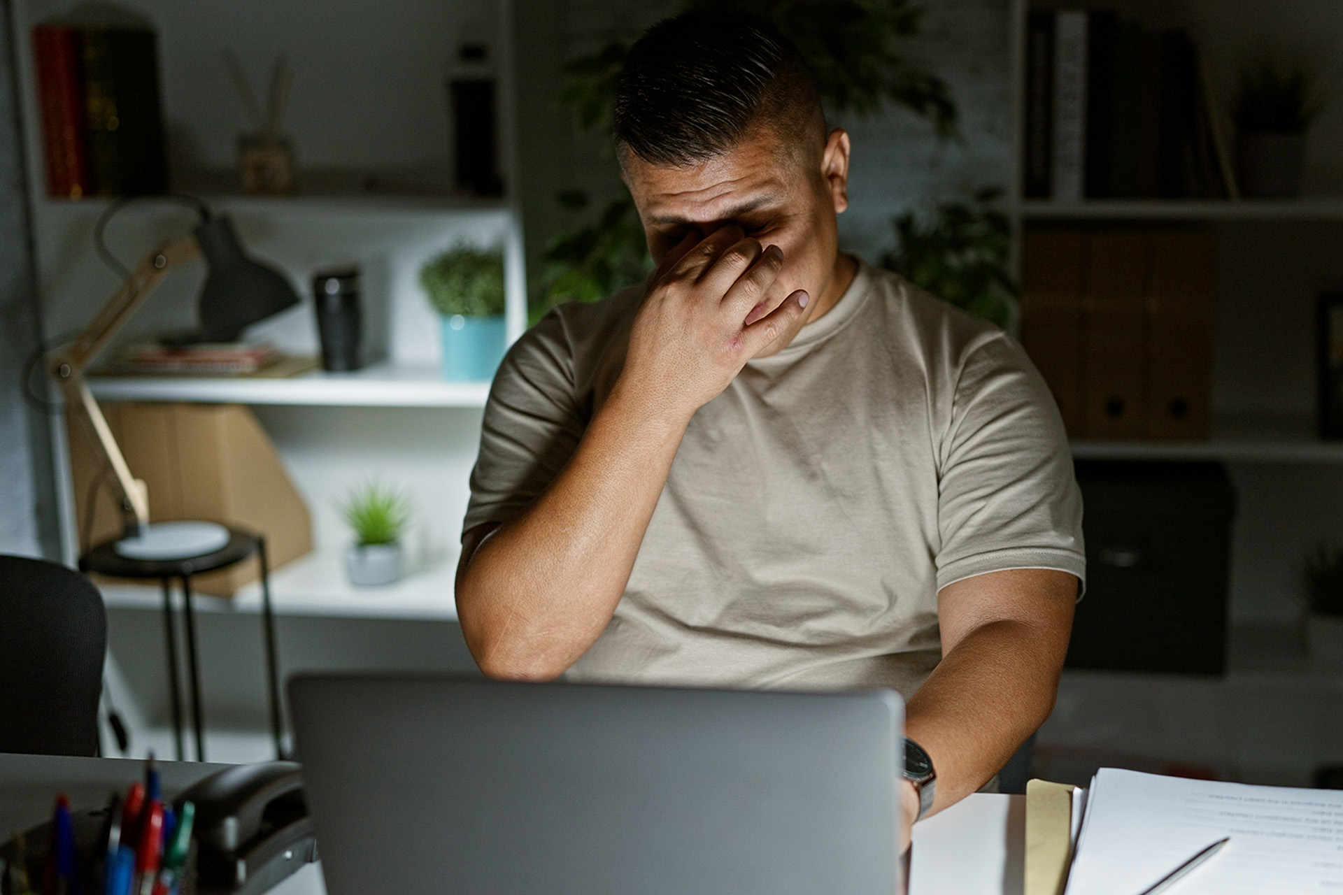 A hardworking father and husband working late at night rubbing his eyes in exhaustion and stress
