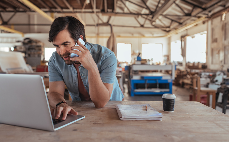 a business owner in a woodshop on a coaching call