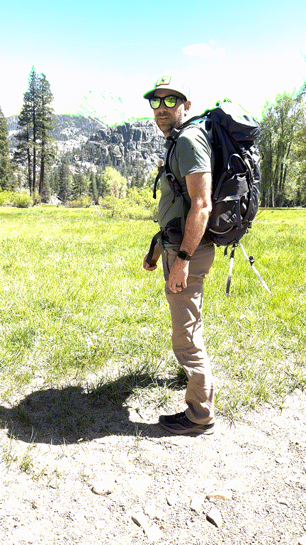 A dirt trail leading into the woods with a weathered trailhead sign, inviting the viewer to take the first step.